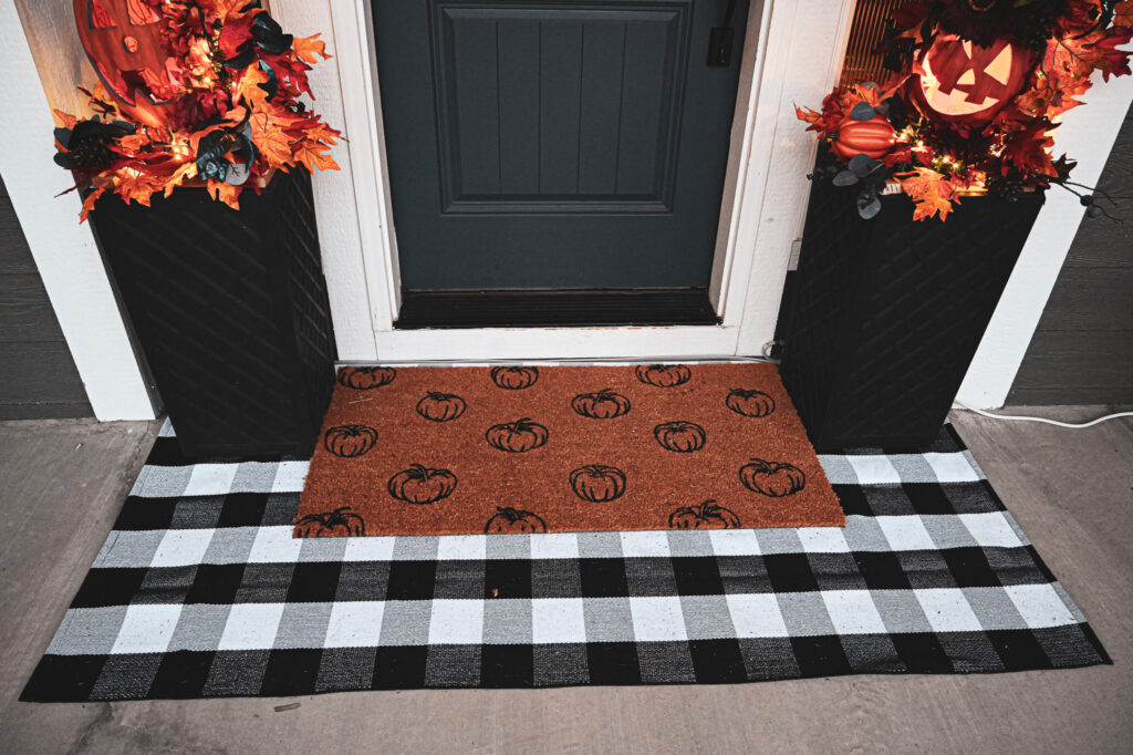 Pumpkin door mat over buffalo plaid rug