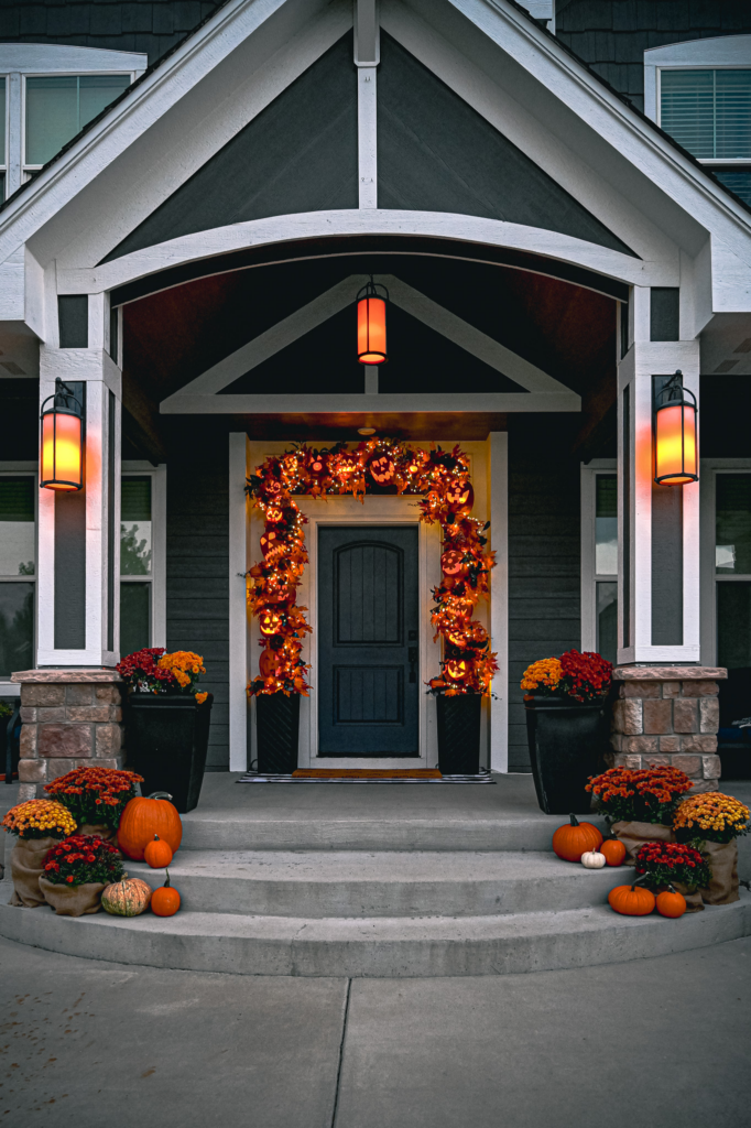 Front porch with jack-o-lantern garland, pumpkins and fall mums.