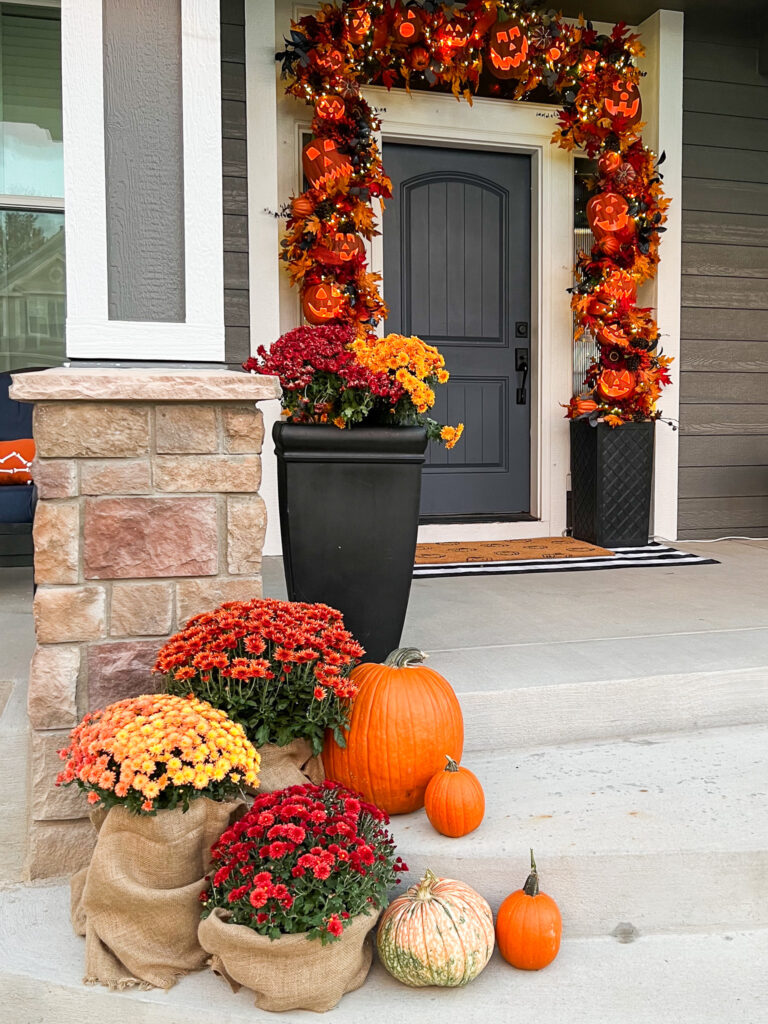 Front porch with colorful mums and pumpkins.